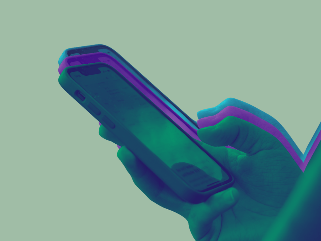 A imagem mostra uma mão segurando um smartphone, com um efeito visual colorido de duplicação nas cores azul e roxa, sobre um fundo verde-claro.